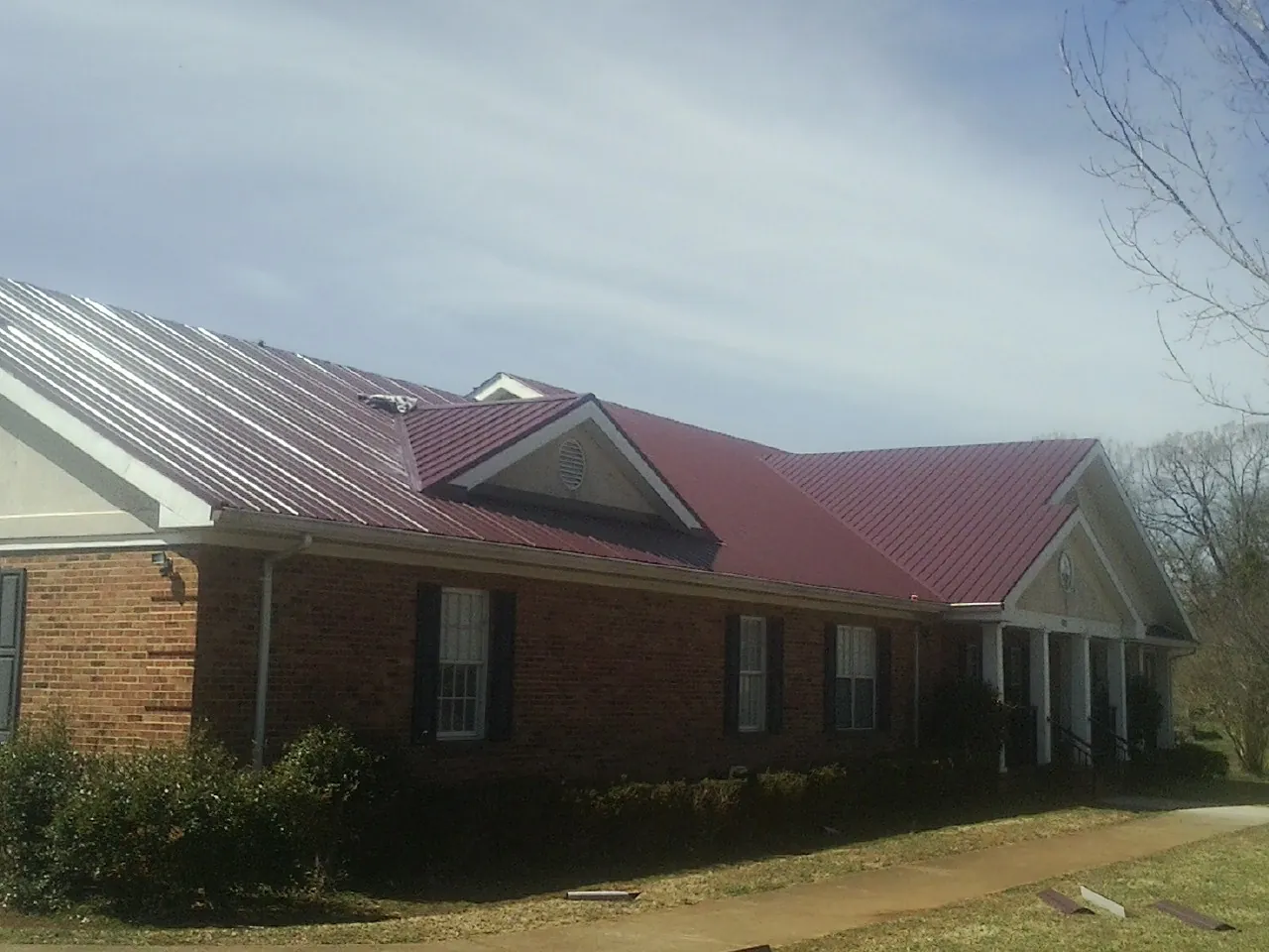 Red metal roof with gabled entries on a long brick building in Clute