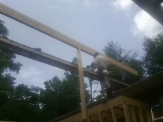 Carpenter setting a ridge beam over a new addition frame — Ice Dam Removal by Roofing Brothers in Clute