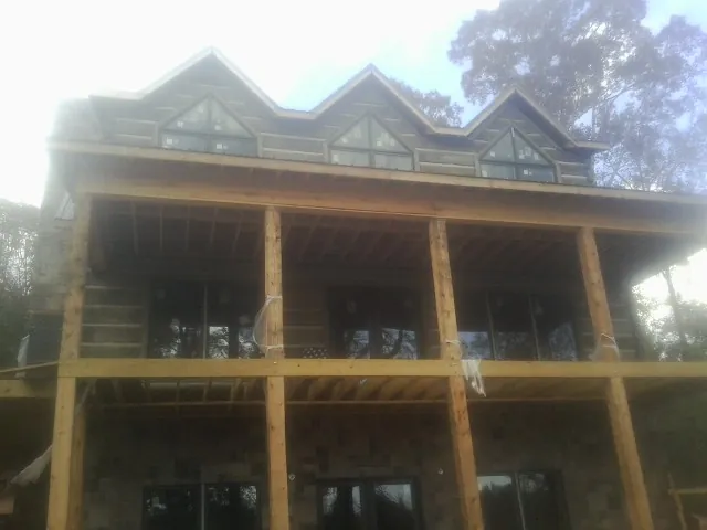 Dormers and porch framing on a large log home under construction — Roof Coating work by our crew in Clute