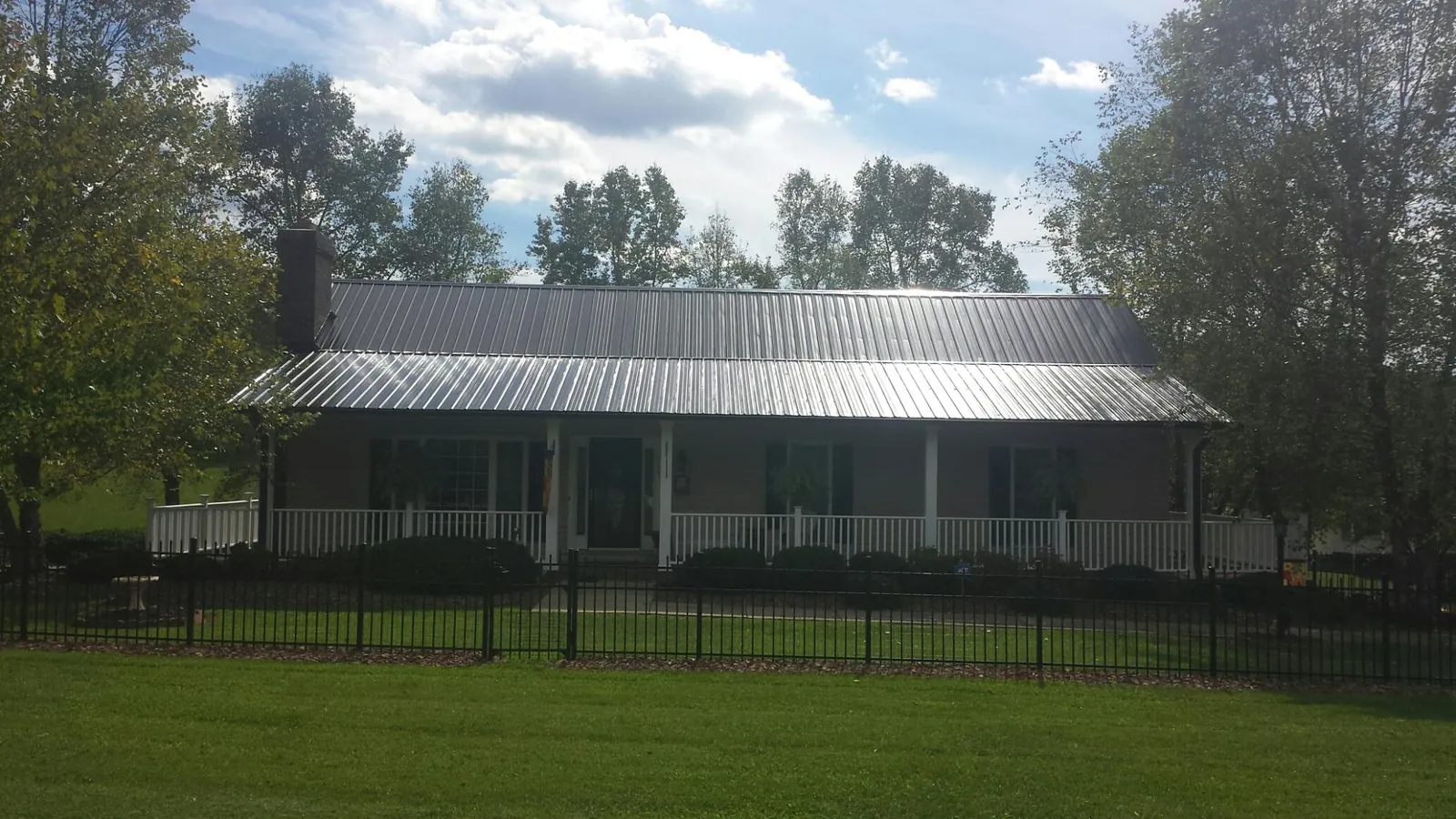 Gray metal roof on a brick ranch with a full width front porch — Gutter Guard Installation work by our crew in Clute