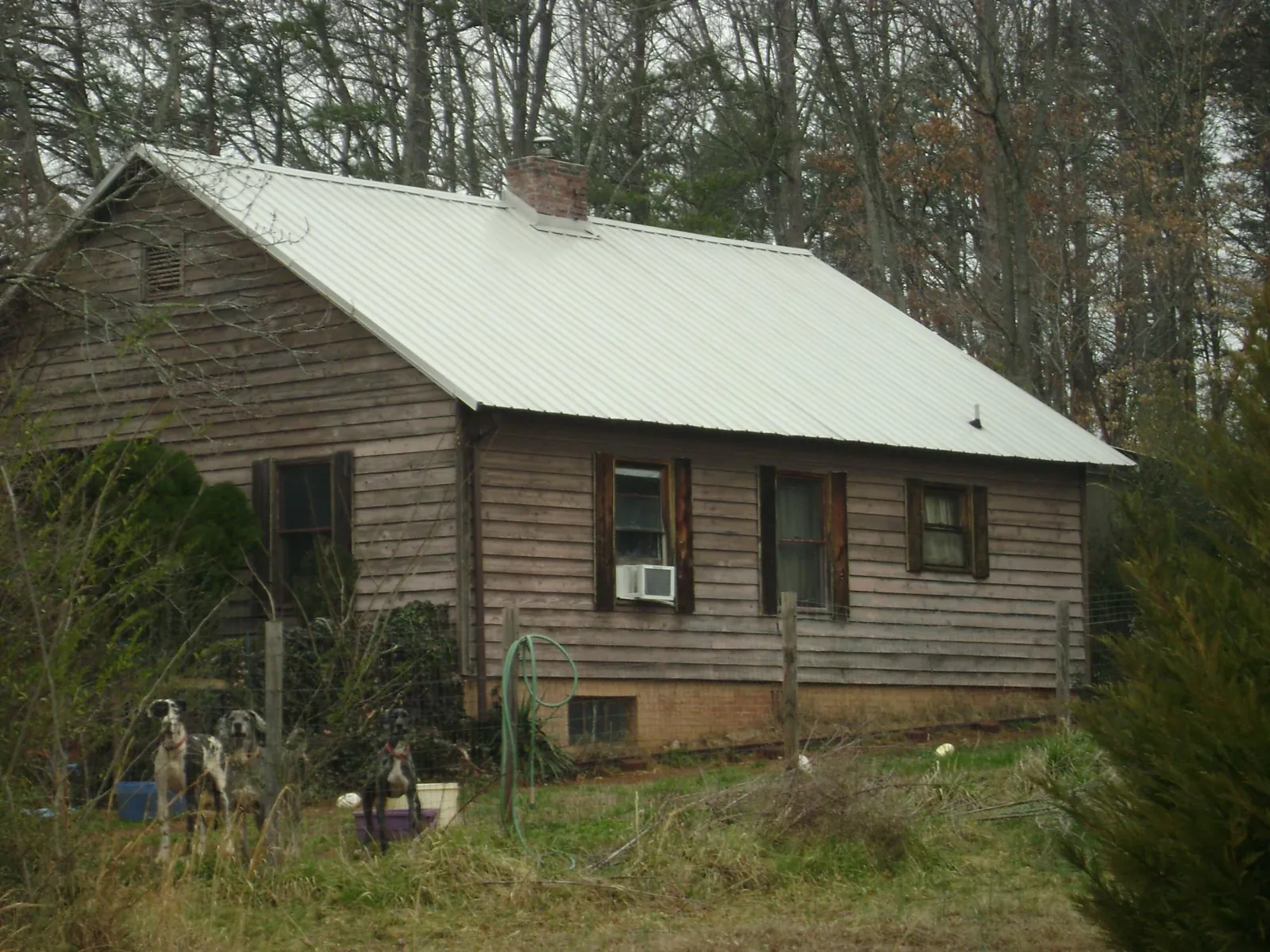 White metal roof on an old wood sided farmhouse, from a Metal Roof Installation job in Clute